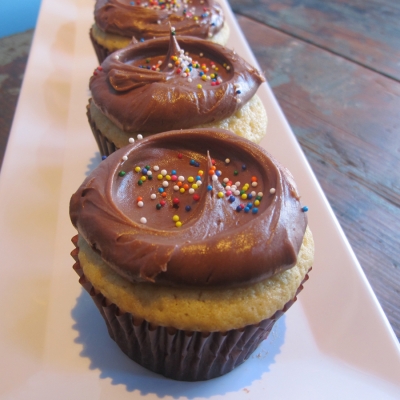 A photo of vanilla cake, chocolate buttercream cupcakes.