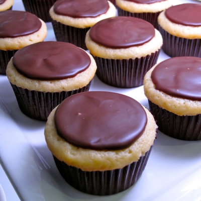 A vanilla cake, pastry cream filling topped with chocolate ganache cupcakes.