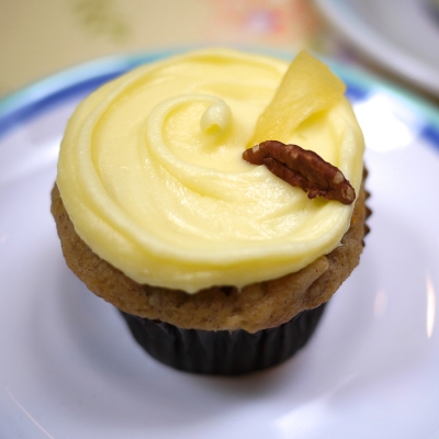 A photo of banana, pineapple and pecan cake with cream cheese frosting cupcake.