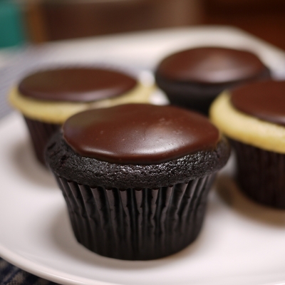 A photo vanilla cake, whipped cream filling topped with chocolate ganache cupcakes.